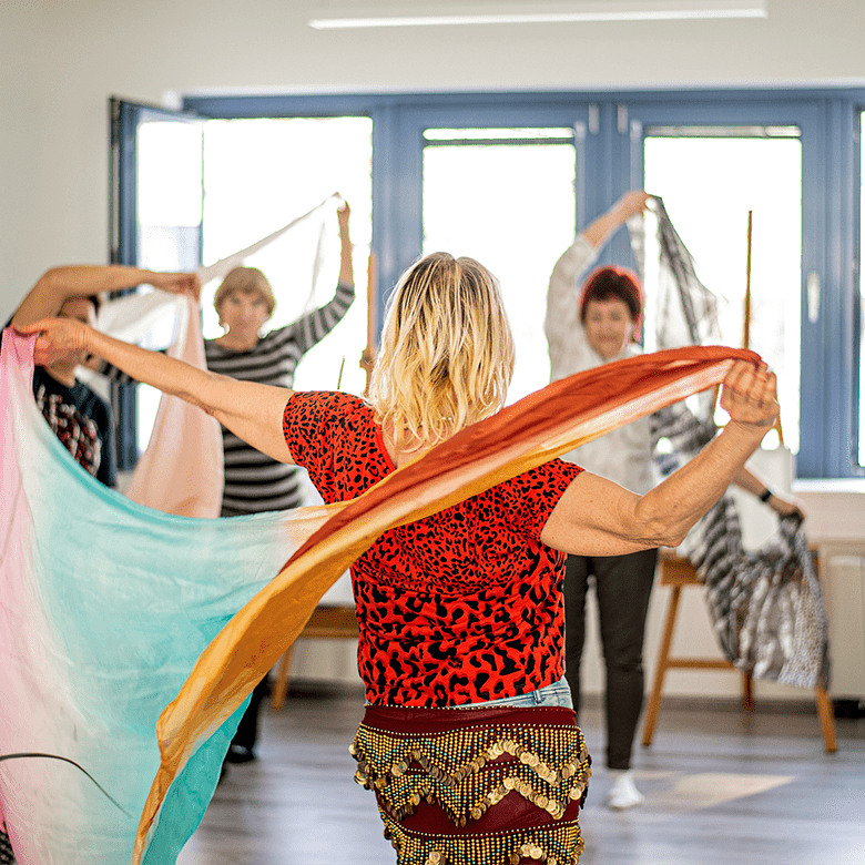 Mehrere Frauen tanzen mit bunten Tüchern