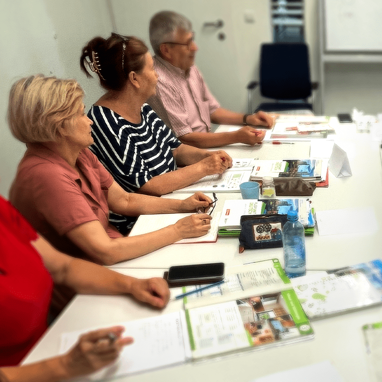 Mehrere Senior*innen sitzen an einem Tisch