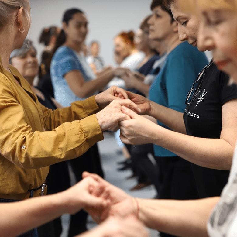 Frauen halten sich an den Händen und tanzen