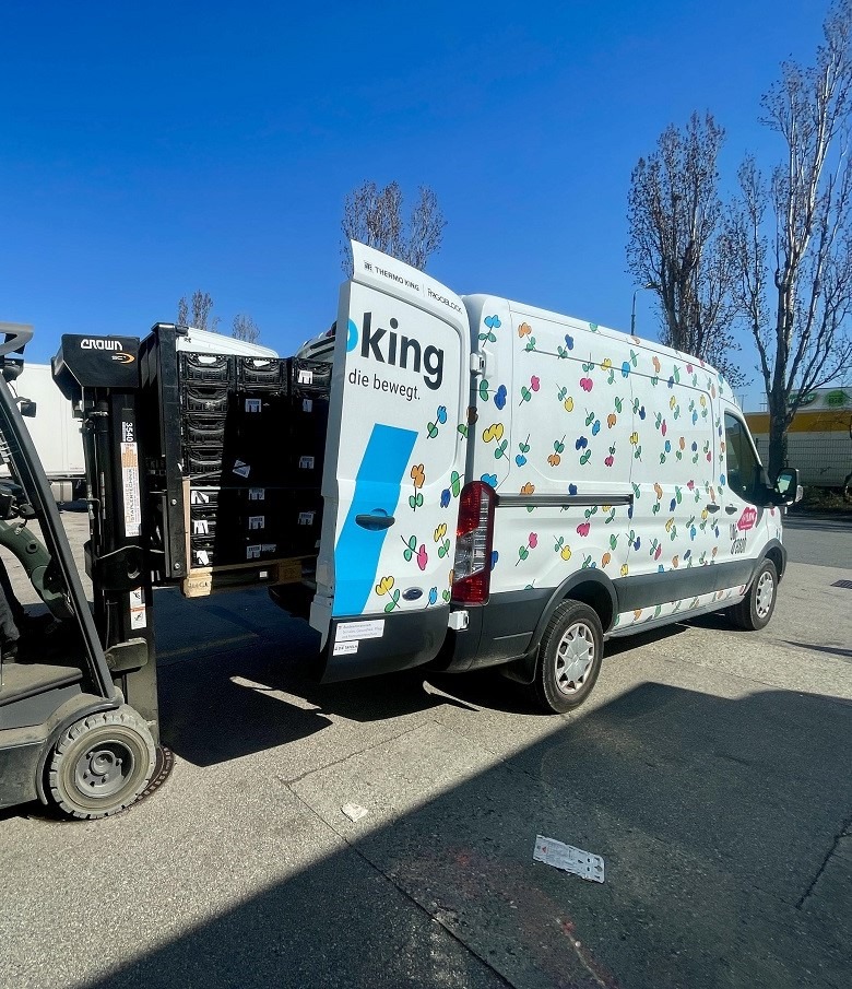 Ein Gabelstapler lädt eine Palette mit schwarzen Kisten in einen Kühltransporter.