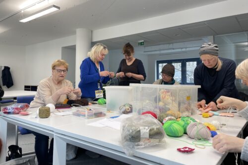 Frauen sitzen an einem Tish und arbeiten mit Wolle