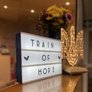 Blumen, Letterbox mit Schriftzug "Train of Hope" und ein leuchtendes ukrainisches Wappen